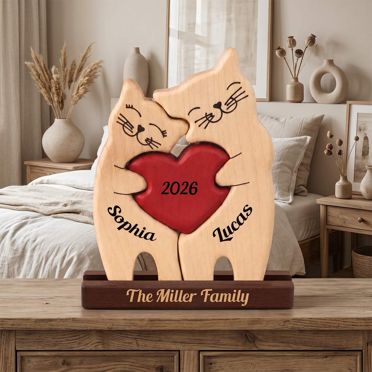 Personalized wooden cat couple figurine holding a red heart with the years 2026, displayed on a wooden stand in a bedroom setting.