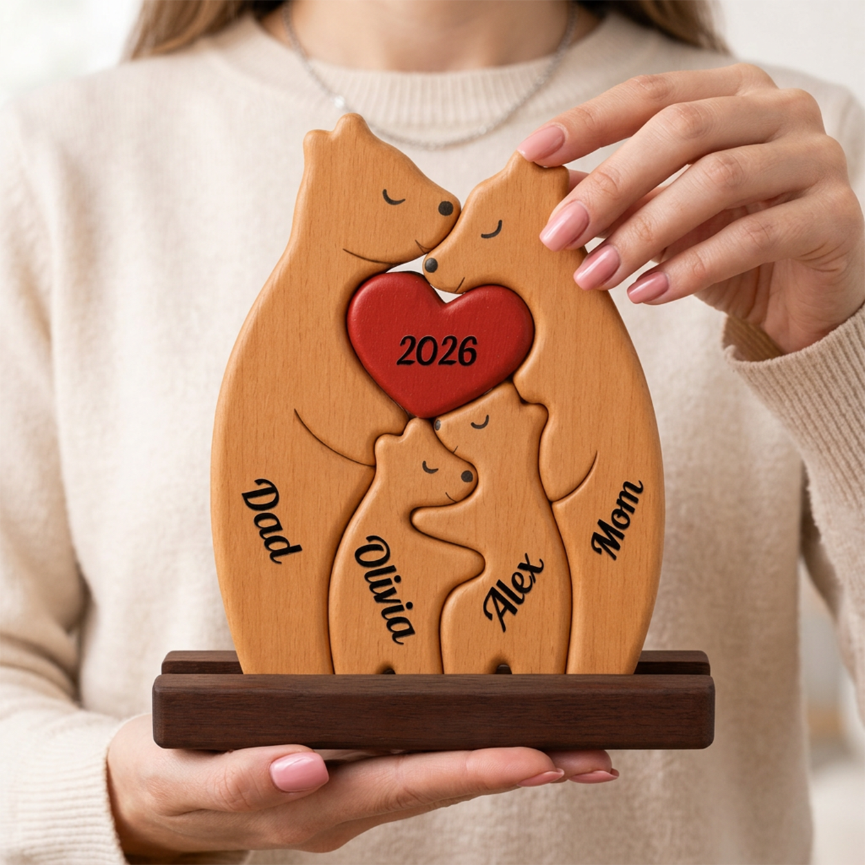 Wooden plaque with family design and '2026' in the center, held by a person.