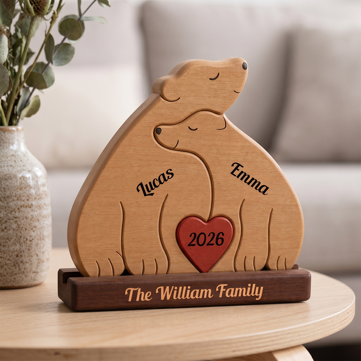 Wooden sculpture of two bear with a heart and names engraved, on a table with a blurred background.