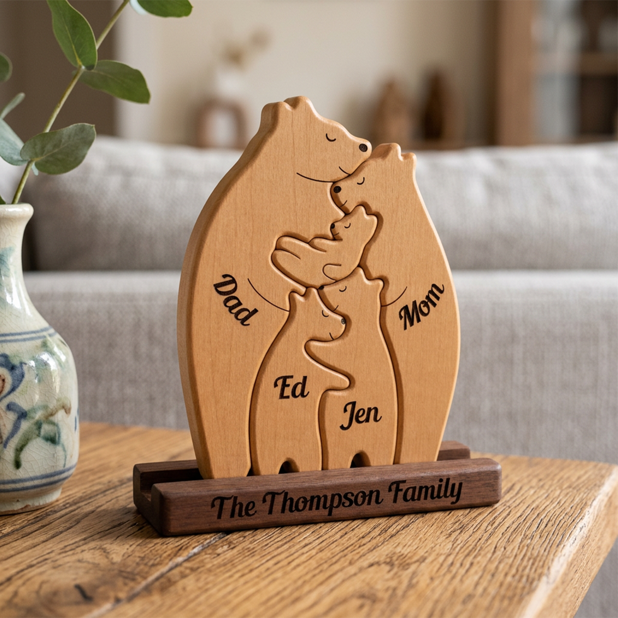 Wooden family sculpture with engraved names on a wooden stand, placed on a table.