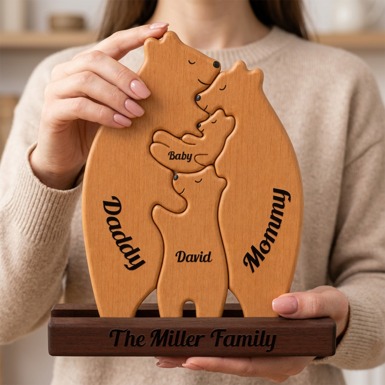 Wooden puzzle shaped like a family of bears with engraved names, held by a person.
