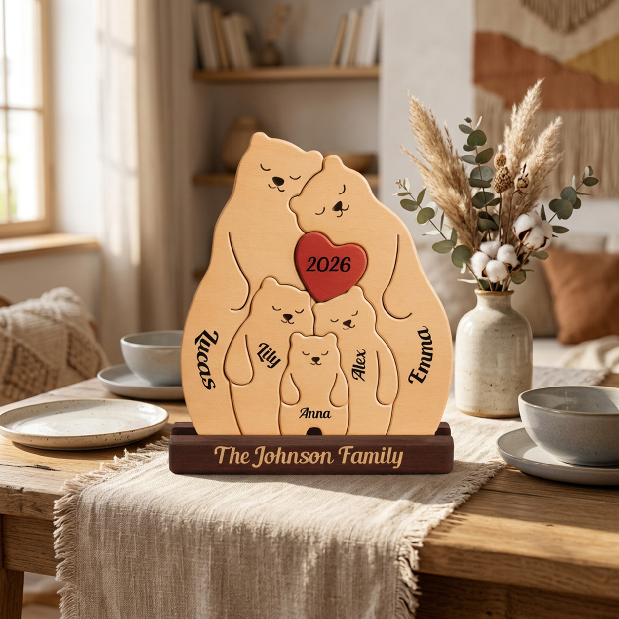 A personalized wooden family plaque shaped like a bear family silhouette, engraved with family names and a red heart reading 2026, displayed on a table in a warm, styled home interior.