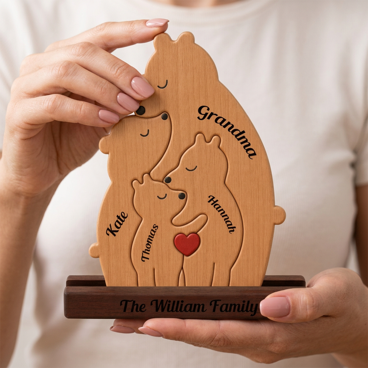 Wooden family sculpture with engraved names held by a person