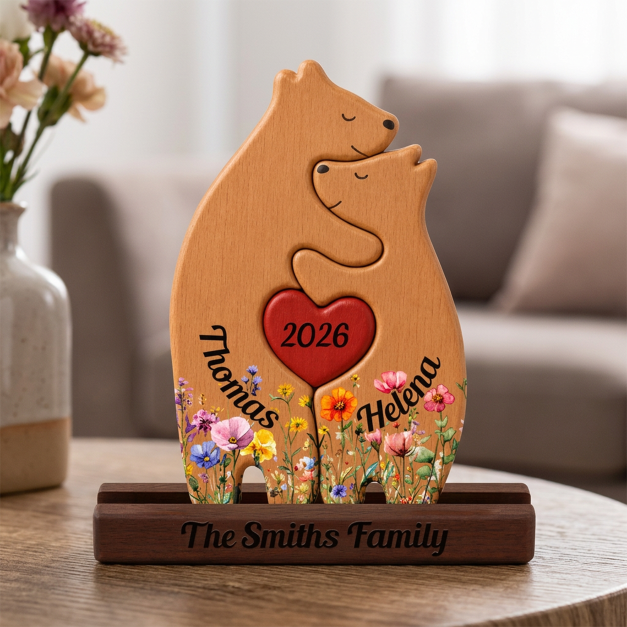 Wooden bear-shape with '2026', 'The  Family' engraved, on a table with a blurred background.