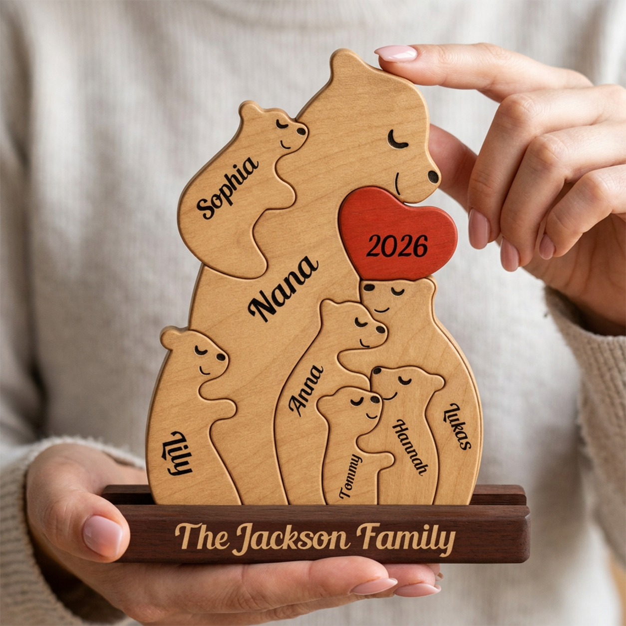 Wooden family sculpture with engraved names and year, held by a person.