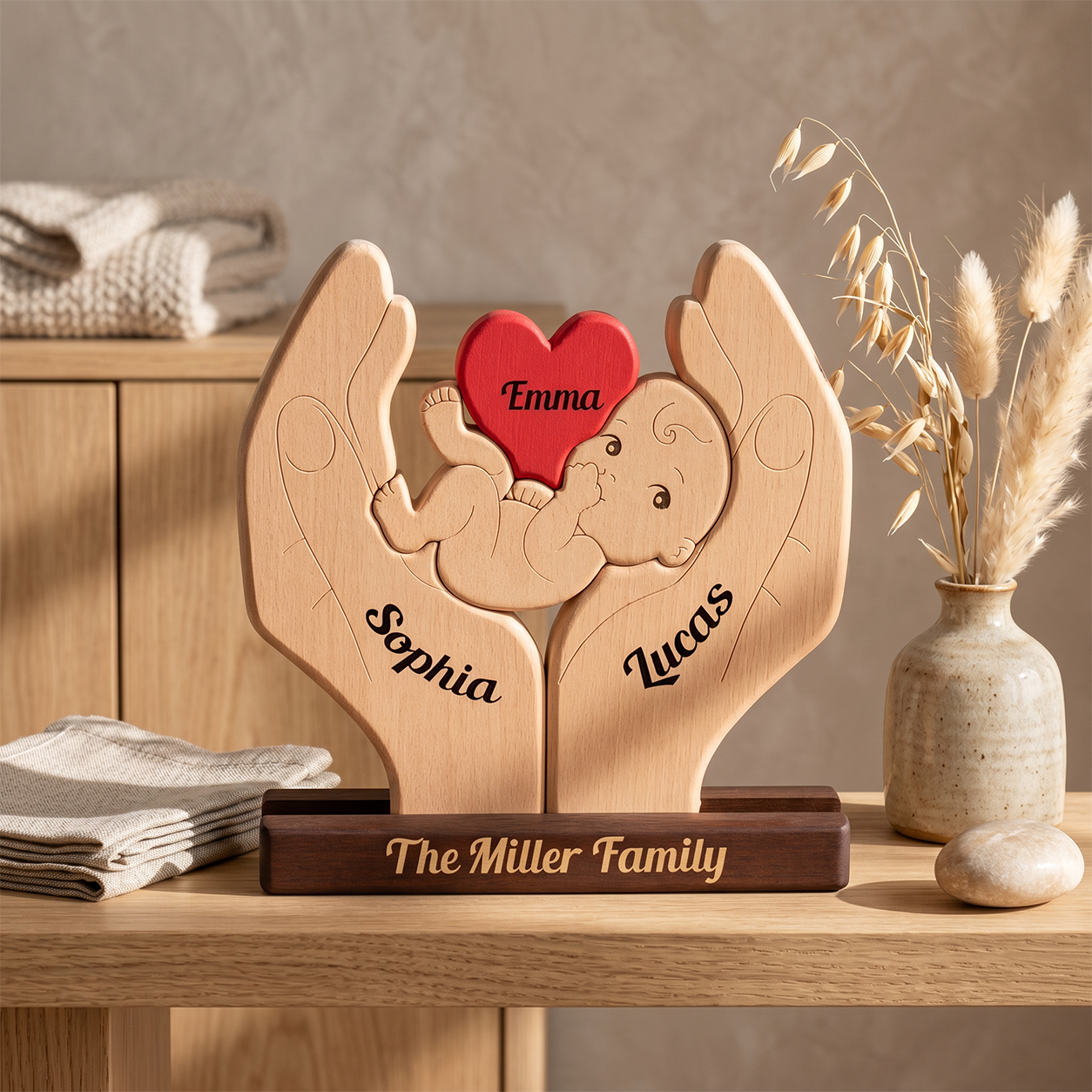 Personalized wooden baby keepsake plaque shaped like two hands holding a baby, with engraved names, displayed on a wooden shelf with home decor props.