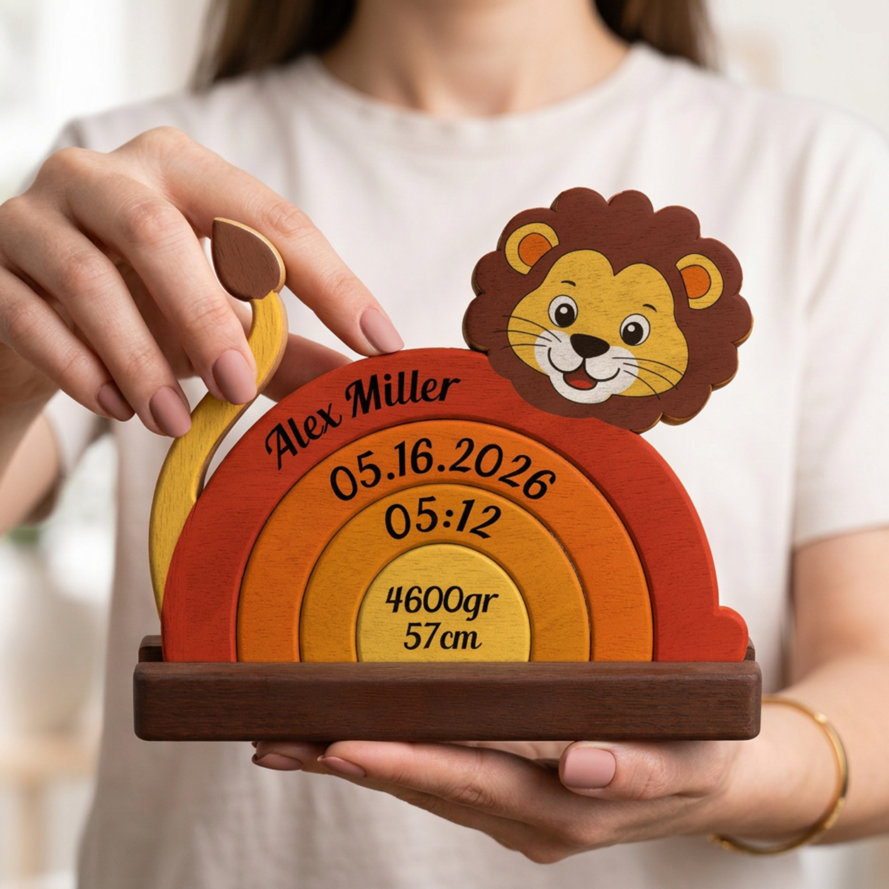 Person holding a wooden baby milestone with lion design and personalized details.