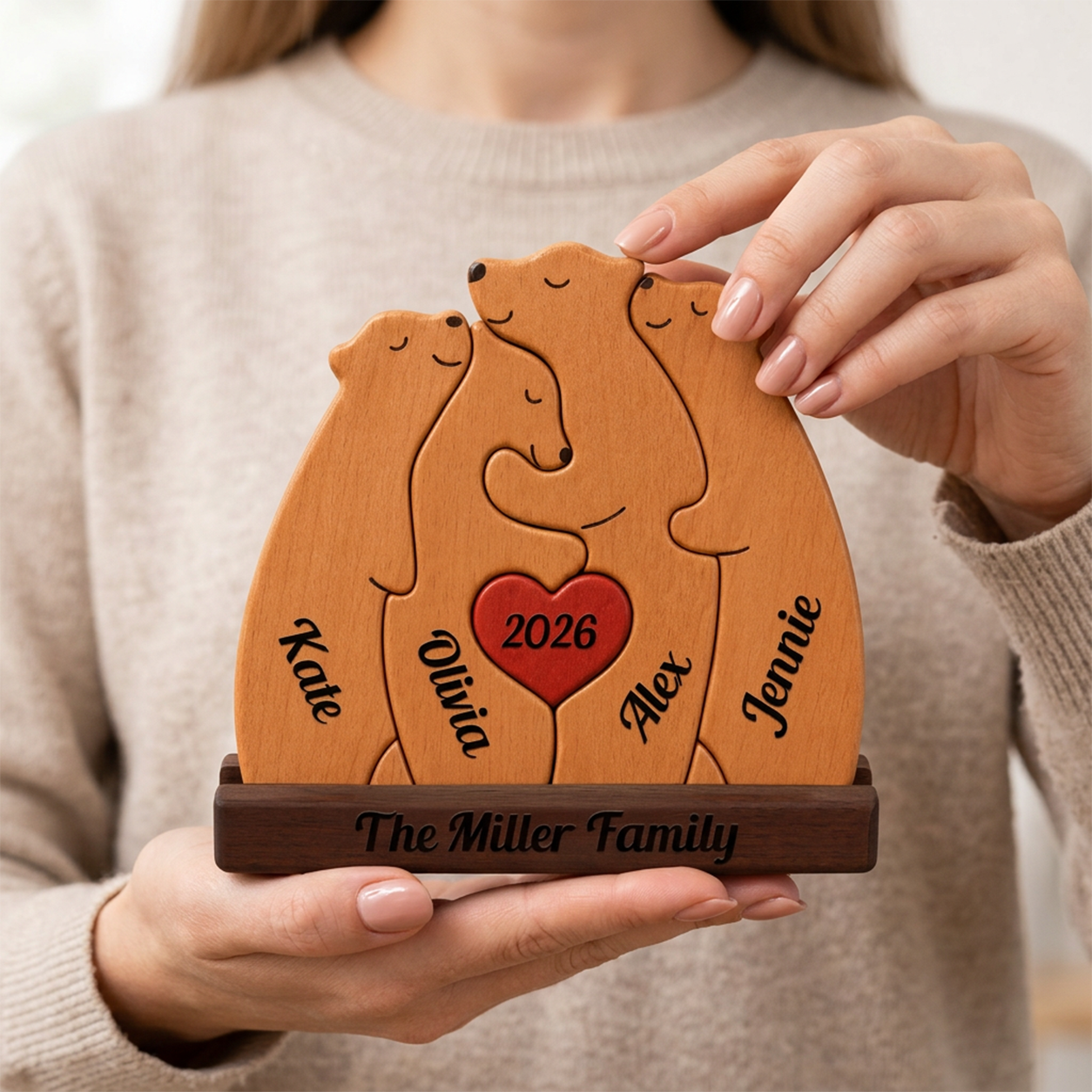Wooden family plaque with engraved names and a heart in the center, held by a person.