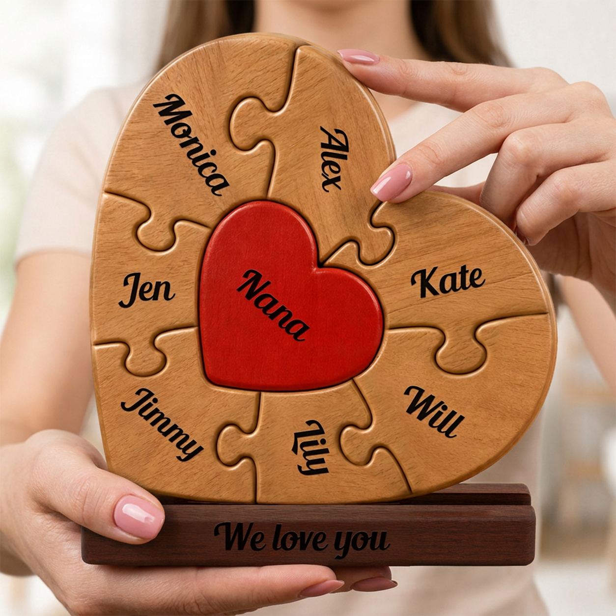 Heart-shaped wooden puzzle with names and a red heart in the center, held by hands.