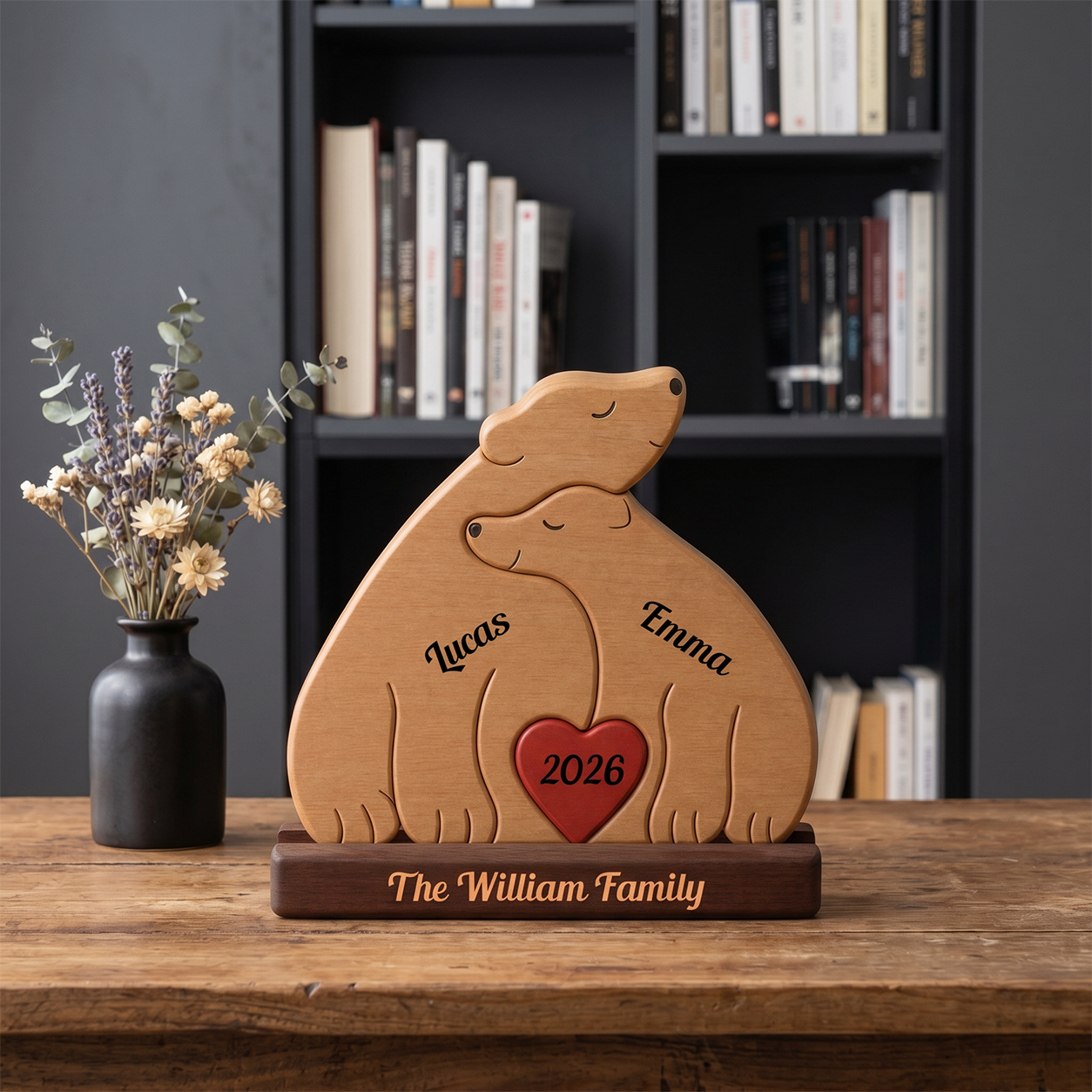 Wooden bear-shaped decoration with engraved names and year on a wooden table, bookshelf in the background.