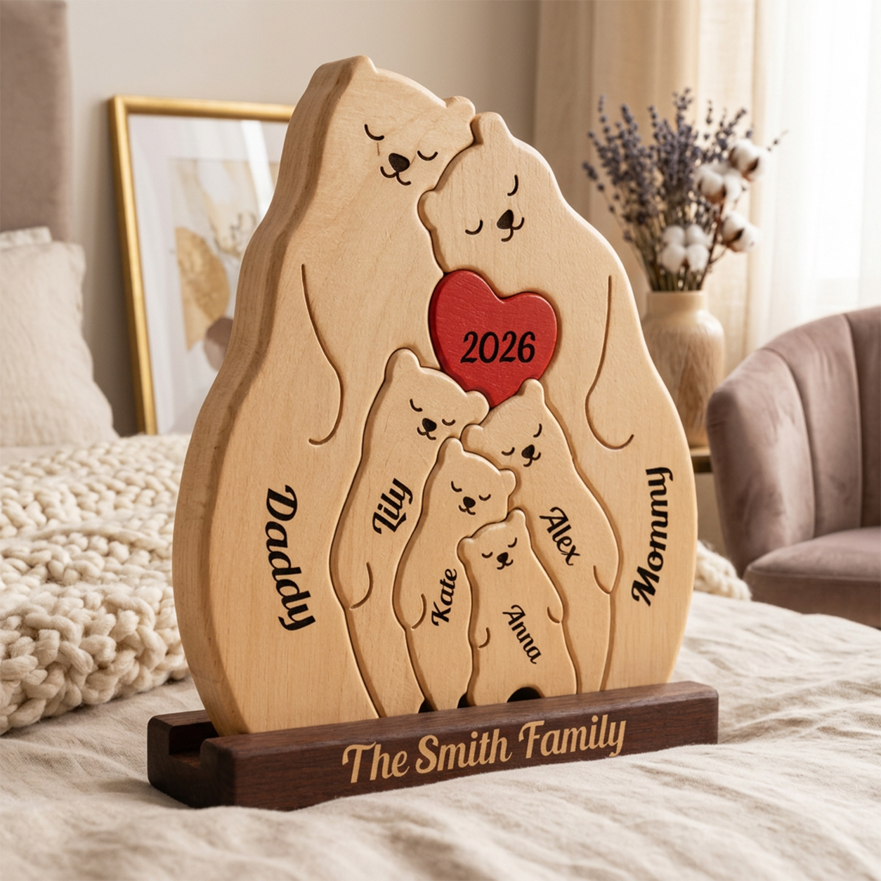 Personalized wooden bear with family names and a red heart reading '2026', displayed on a bed in a cozy bedroom setting.