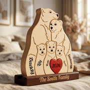 Personalized wooden polar bear family plaque on a dark wood base, engraved with five polar bear figures, names, and a red heart reading 2026, shown on a bed in a softly lit bedroom.