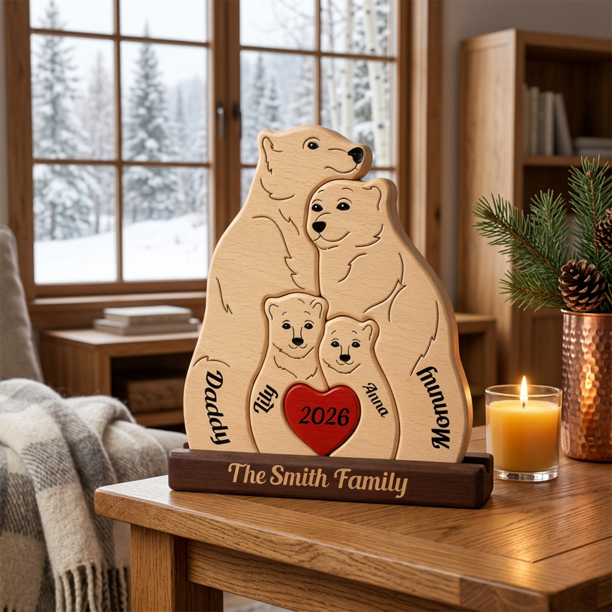 Personalized wooden family plaque shaped like a bear family, engraved with names and a red heart reading '2026', displayed on a wooden table in a cozy living room setting with a lit candle nearby.