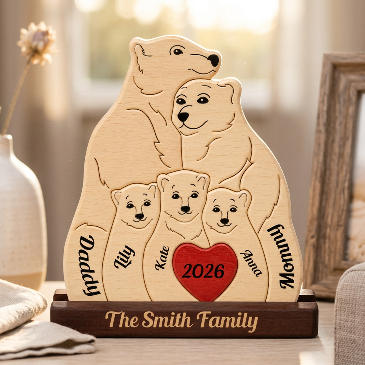 Personalized wooden family plaque shaped like a polar bear family, engraved with names, plus a red heart with '2026' in the center, displayed on a wooden base in a softly lit indoor setting.